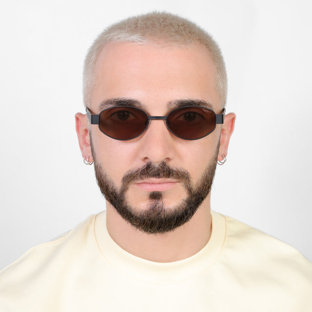 Model with a platinum buzzcut wearing Nesso Sunglasses Matte Black with Brown