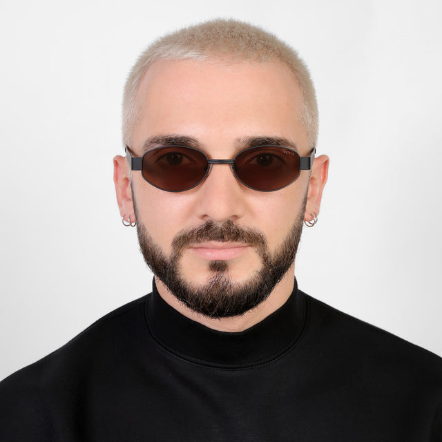 Model with a platinum buzzcut wearing Nesso Sunglasses Matte Black with Brown