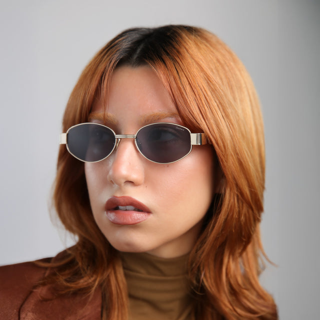 Another angle of model with red hair wearing Nesso Sunglasses Gold with Grey