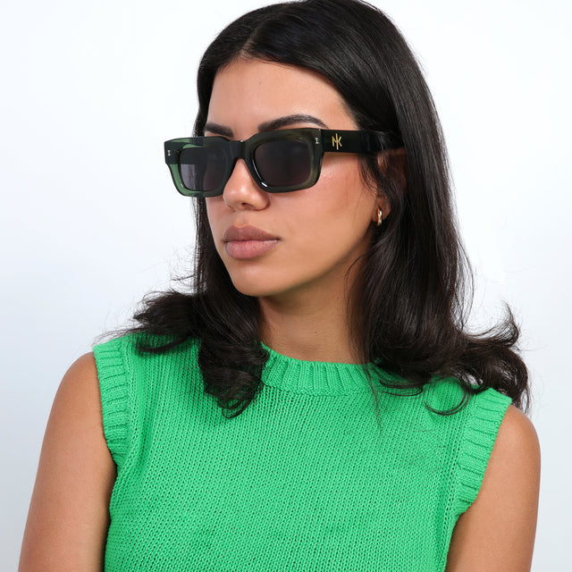 Brunette model in a bright green sweatervest wearing Nick Kyrgios x illesteva 2 Sunglasses Pine with Grey Flat