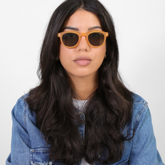 Brunette model in a denim jacket wearing PopUp Bagels x illesteva Sunglasses Matte Honey Gold with Olive