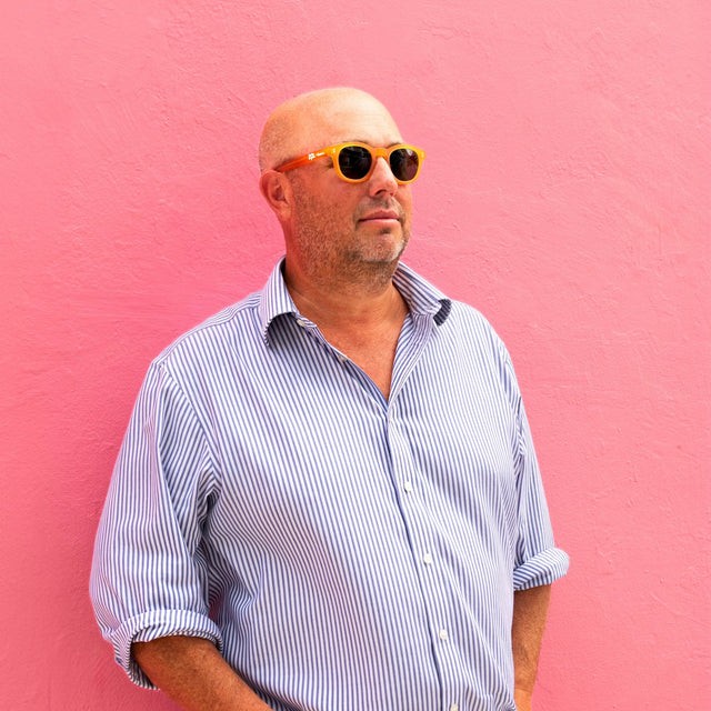 Founder of PopUp Bagels against a pink wall wearing PopUp Bagels x illesteva Sunglasses Matte Honey Gold with Olive