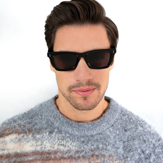 Model with short brown hair combed sideways wearing Portugal Sunglasses Black with Grey Flat