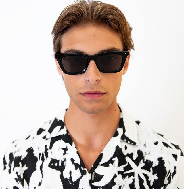 Model with short brown hair pushed back wearing Portugal Sunglasses Black with Grey Flat