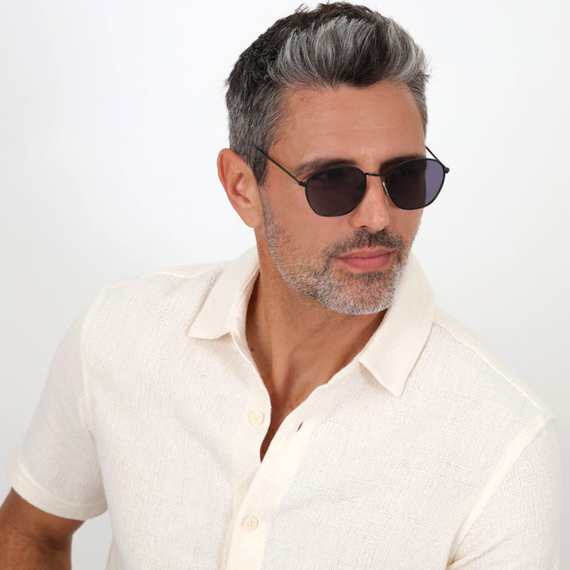 Model with salt and pepper hair and beard wearing Prince Sunglasses Matte Black with Grey Flat