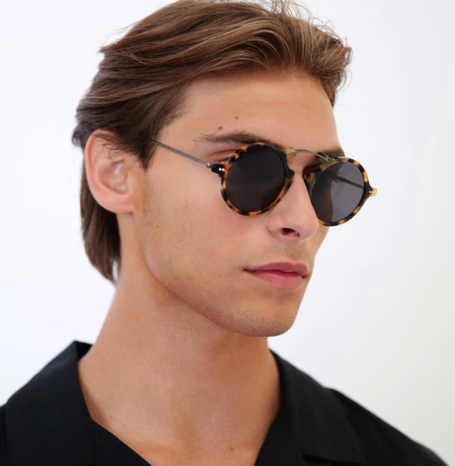 Model with short, brown hair pushed back wearing Roma II Sunglasses Tortoise with Grey Flat