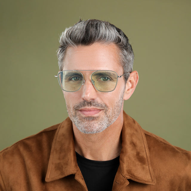 Man with salt and pepper hair and beard in a brown suede jacket wearing Samos Sunglasses Silver with Mint Flat See Through