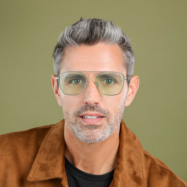 Another angle of man in a brown suede jacket wearing Samos Sunglasses Silver with Mint Flat See Through
