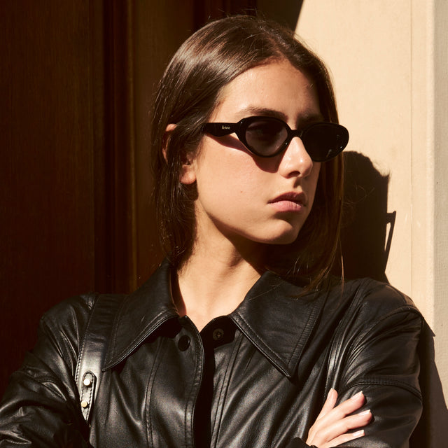 Woman in Paris wearing a black leather jacket wearing Sheila Sunglasses Black with Grey Flat