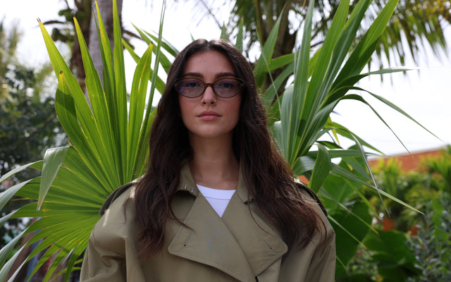 Woman in a trench coat wearing the new Sheila Sunglasses in Moss