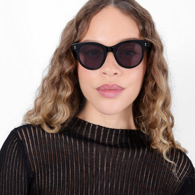 Brunette model with ombré, natural curls wearing Sicilia Sunglasses Black with Grey