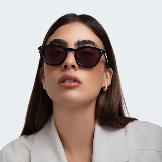 Woman in a grey blazer wearing Slope Sunglasses Black with Plum See Through