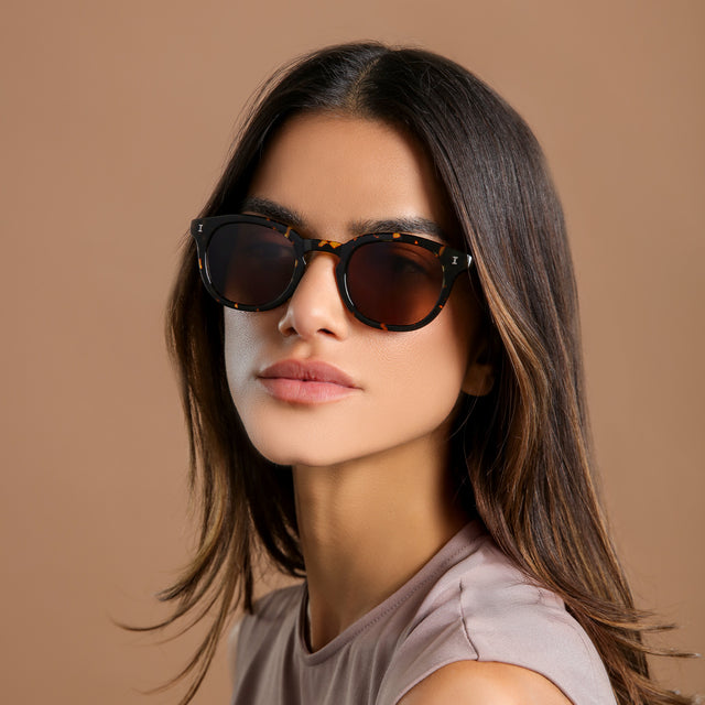 Brunette woman in a clay blouse wearing Slope Sunglasses Flame with Brown