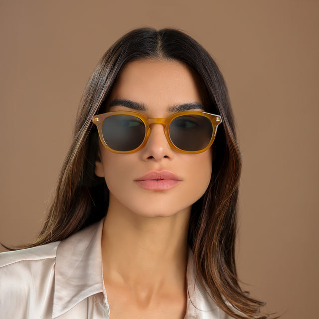 Another angle of brunette woman in a cream silk blouse wearing Slope Sunglasses Honey Gold with Olive