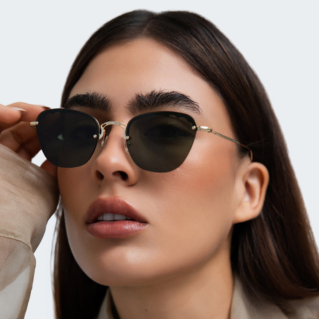 Close up of woman in a beige blouse wearing Sorrento Sunglasses Gold with Olive Flat
