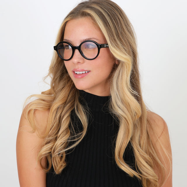 Blonde model with loose curls wearing The Met x illesteva Optical Black Optical