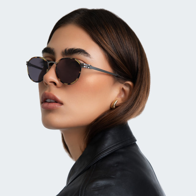 Another angle of woman in a black leather blouse wearing Tompkins Titanium Sunglasses Tortoise/Matte Silver with Grey