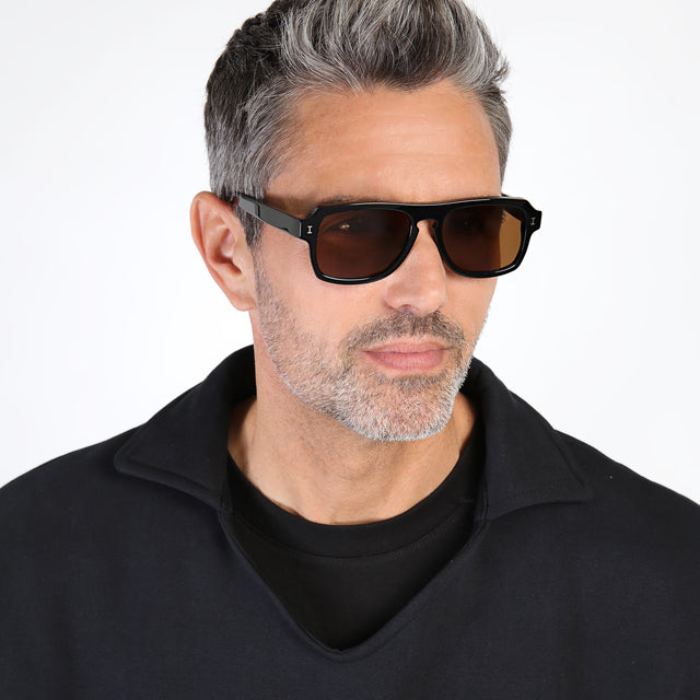 Model with salt and pepper hair and beard looking left wearing Trancoso Sunglasses Black with Brown