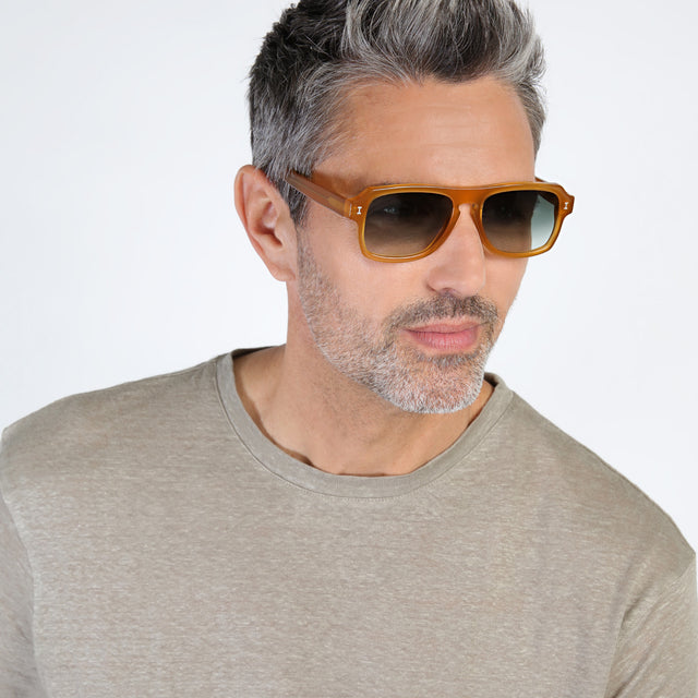 Model with salt and pepper hair and beard looking left wearing Trancoso Sunglasses Honey with Olive Gradient