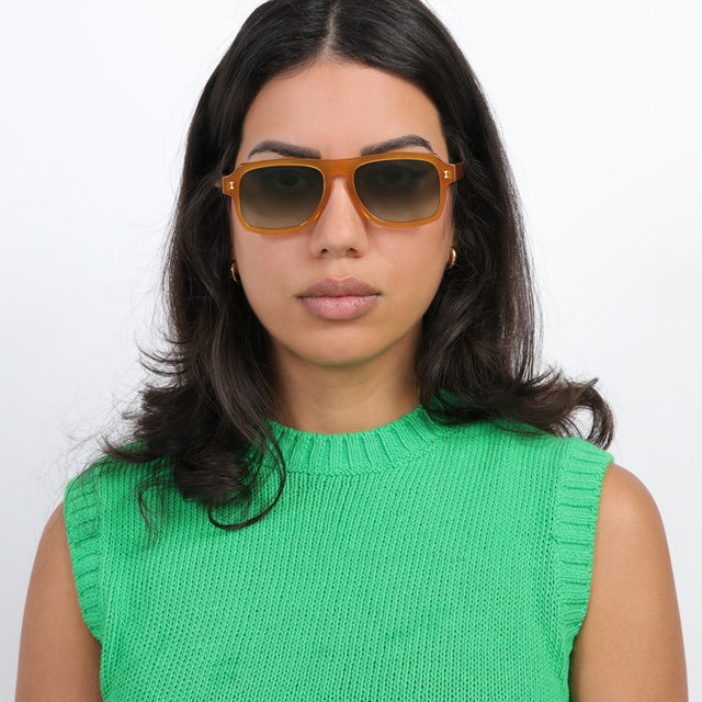 Brunette model with loose curls wearing Trancoso Sunglasses Honey with Olive Gradient