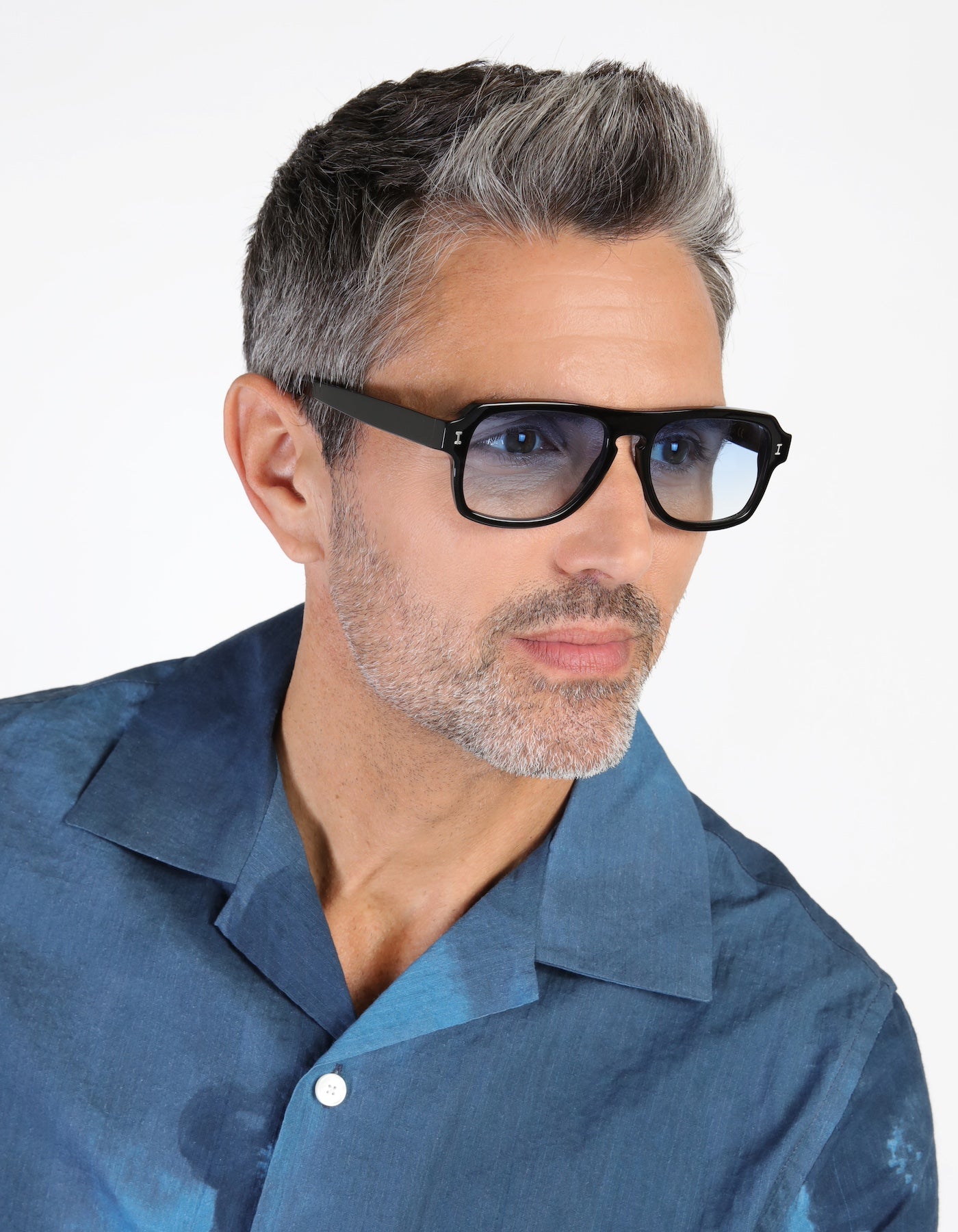 Model with salt and pepper hair and bear wearing Trancoso Sunglasses in Black with Blue