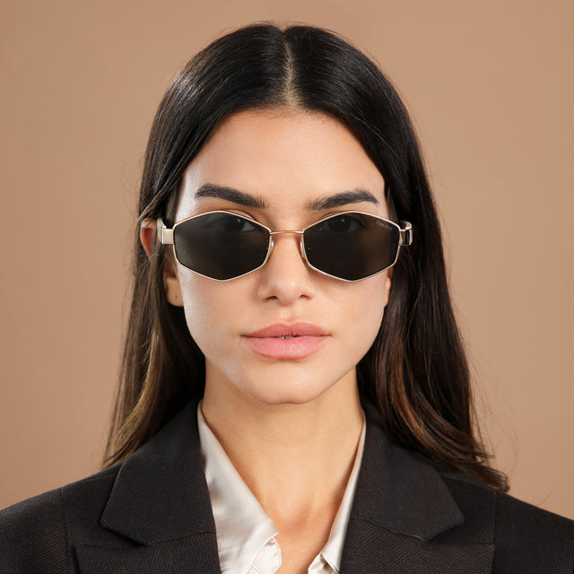 Brunette model in a black blazer wearing Tucson Sunglasses Rose Gold/Cream with Grey