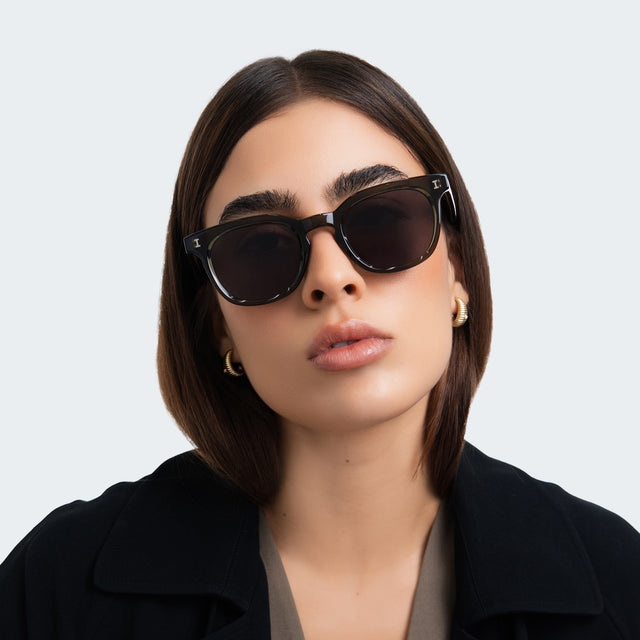 Woman in a black coat wearing Veneto Sunglasses Green with Grey Flat
