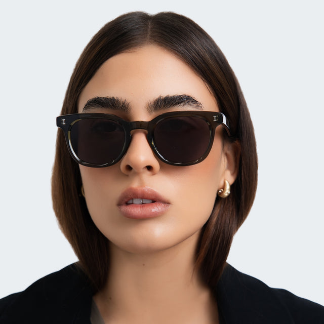 Close up of woman in a black coat wearing Veneto Sunglasses Green with Grey Flat