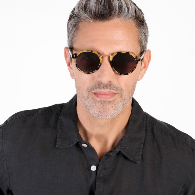 Model with salt and pepper hair and beard wearing Village Sunglasses Tortoise/Gold with Grey