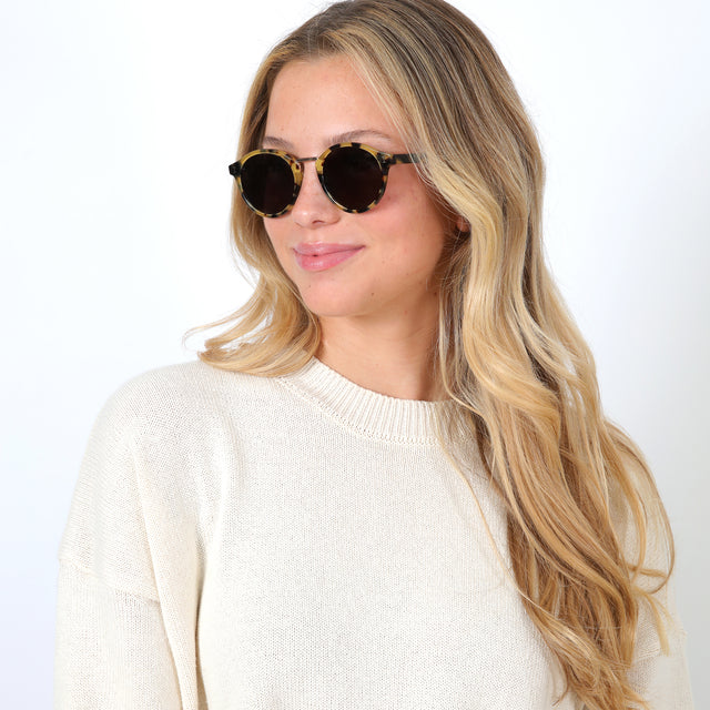 Blonde model looking right wearing Village Sunglasses Tortoise/Gold with Grey