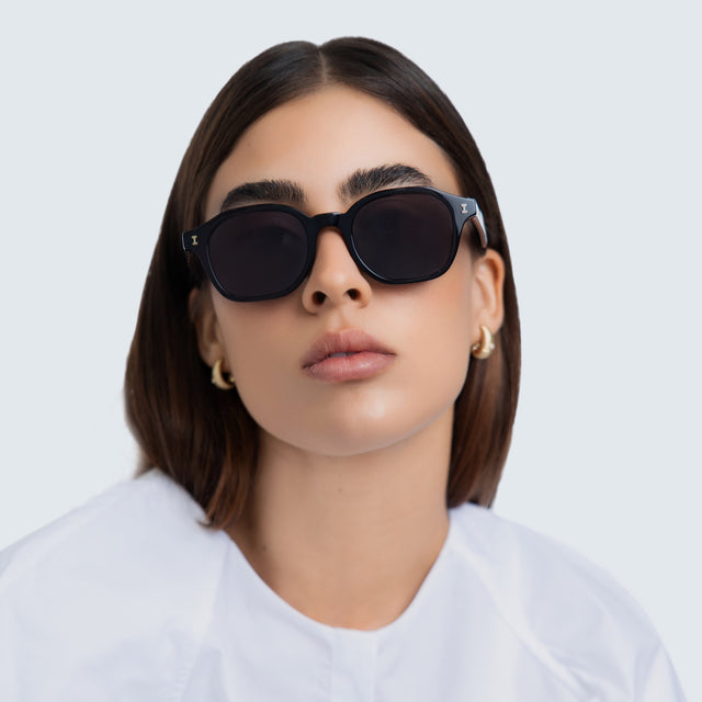 Woman in a white blouse wearing Will Sunglasses Black/Gold with Grey