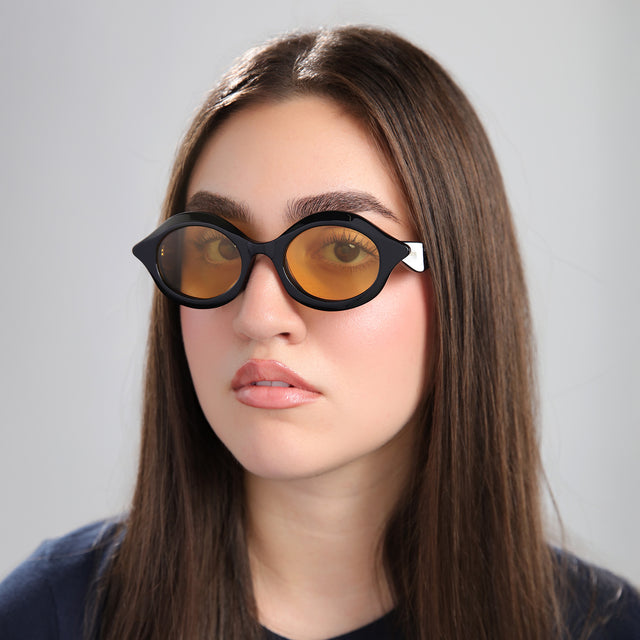 Another angle of brunette woman in a navy blouse wearing Willow Sunglasses Black with Honey See Through