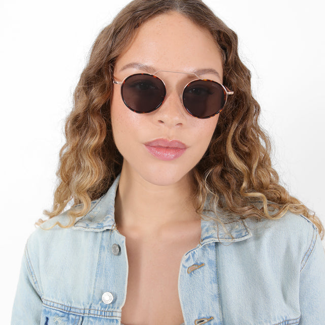 Brunette model with ombré, natural curls wearing Wynwood Ace Sunglasses Star Tortoise/Rose Gold with Grey Flat