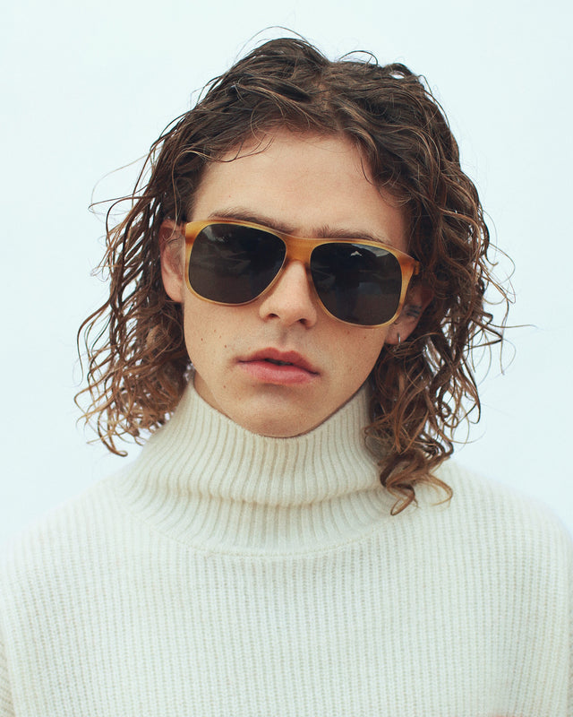 Model with wavy brown hair in a white turtleneck wearing Dionne Sunglasses Caramel Havana with Olive