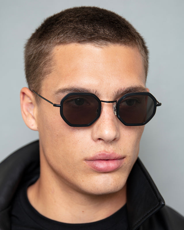 Model with buzzcut wearing Dylan Tate Sunglasses Matte Black with Grey Flat Lenses