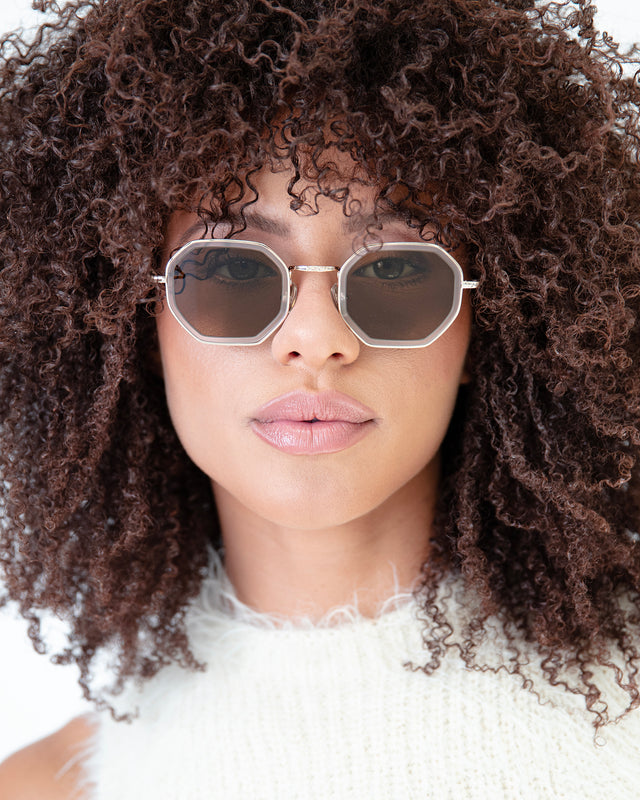 Brunette model with afro-curly hair wearing Dylan Tate Sunglasses Matte Clear/Gold with Brown Flat