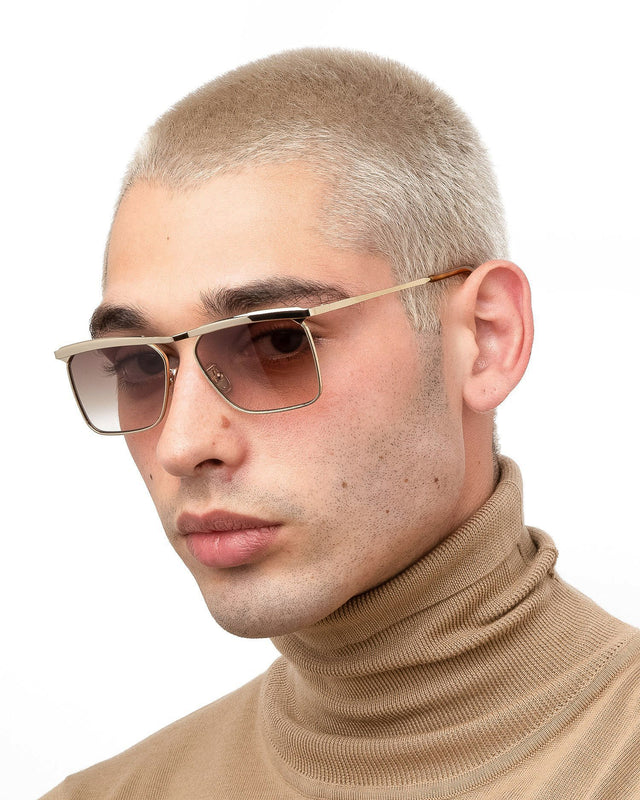 Model with blonde buzzcut wearing PCH Sunglasses Gold with Brown Flat Gradient Lenses