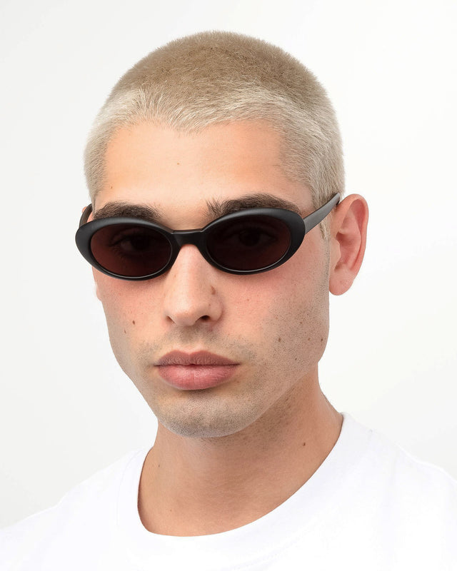 Model with blonde buzzcut wearing Seattle Sunglasses Matte Black with Grey Flat Lenses