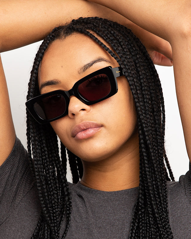 Brunette model with box braids wearing Wilson Sunglasses Black with Grey Flat